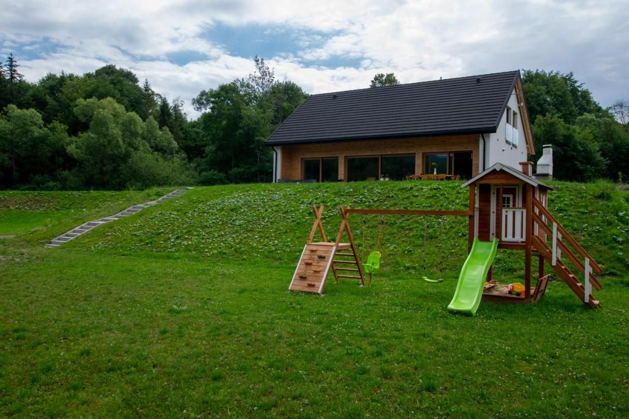 Drewniany plac zabaw na trawie poniżej domu